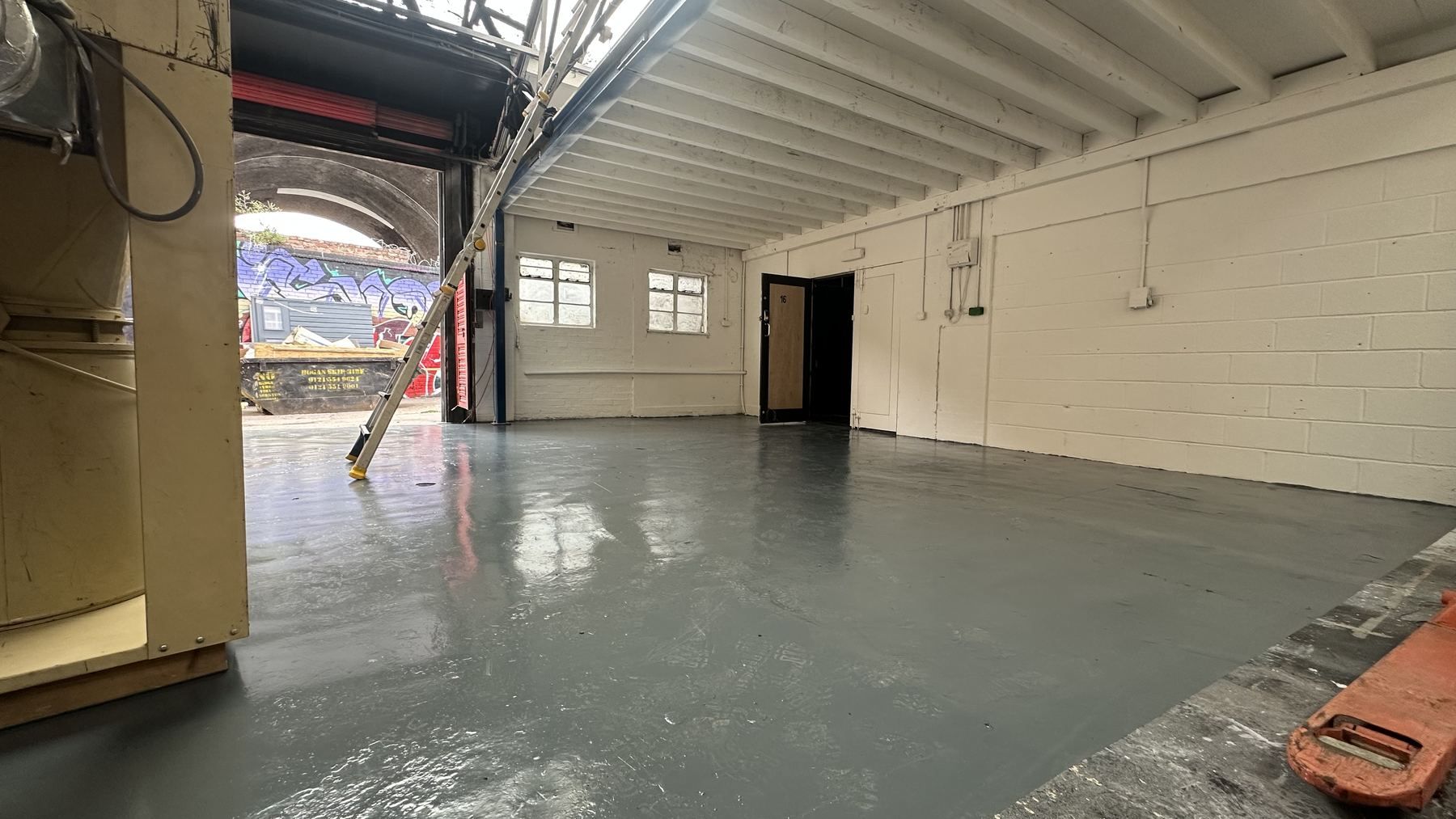 A clean bay with a painted grey floor, white walls and a roller door open to the street