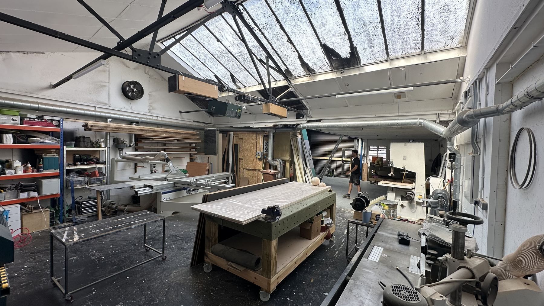 The machine shop under skylights, with saws, benches and racking