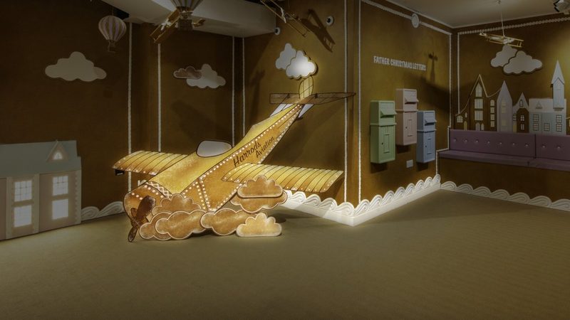 A gold paper aeroplane and paper houses in a themed pop-up installation