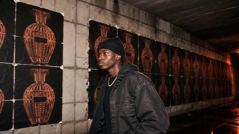 A wall of large printed posters of a flacon with a man standing in front of them
