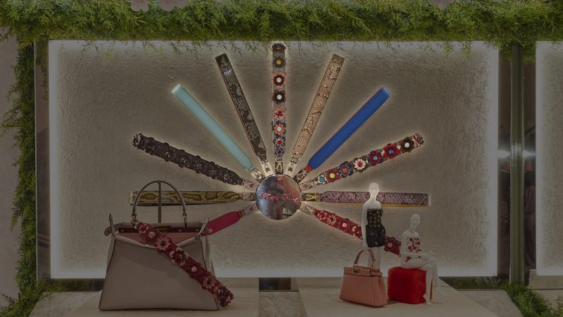 A shop window display of handbags with colourful straps fanned out in a sunburst